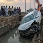 ग्रेटर नोएडा में बाइक सवार को बचाने के चक्कर में गड्ढे में गिरी कार, बाल-बाल बचा चालक